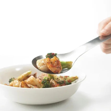 Suqu serving spoon lifting stir-fried vegetables from a bowl