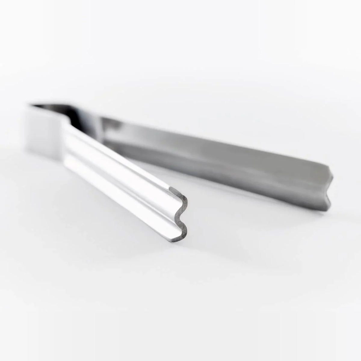 Shiboru stainless tongs lying on a white surface