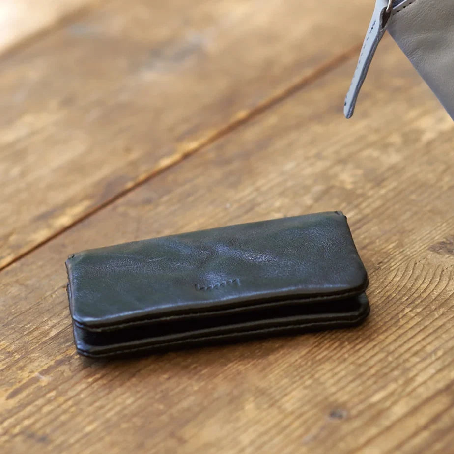 hmny black leather card case on a wooden table