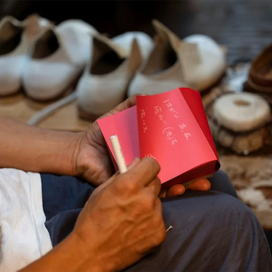 Writing on a red ITO BINDERY memo block in a workshop