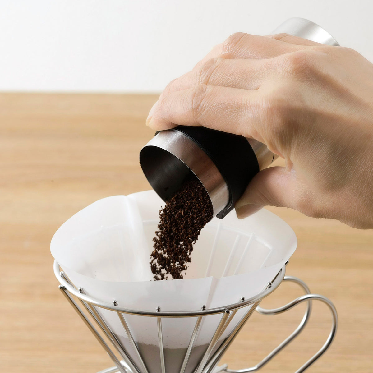 Pouring freshly ground coffee into a paper filter