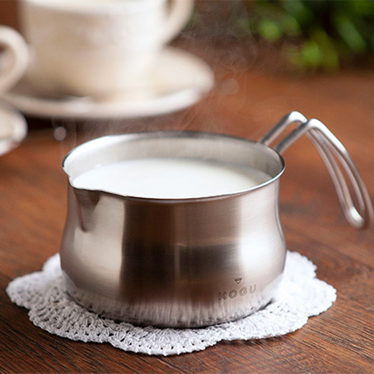 Stainless steel milk pan with warm milk on a lace doily
