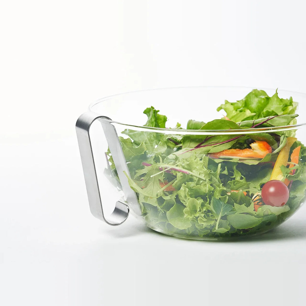 Oros Handy grater hooked on the rim of a salad bowl