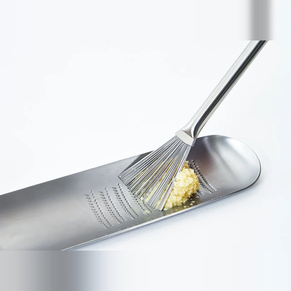 Hake brush sweeping grated ginger on the Oros grater