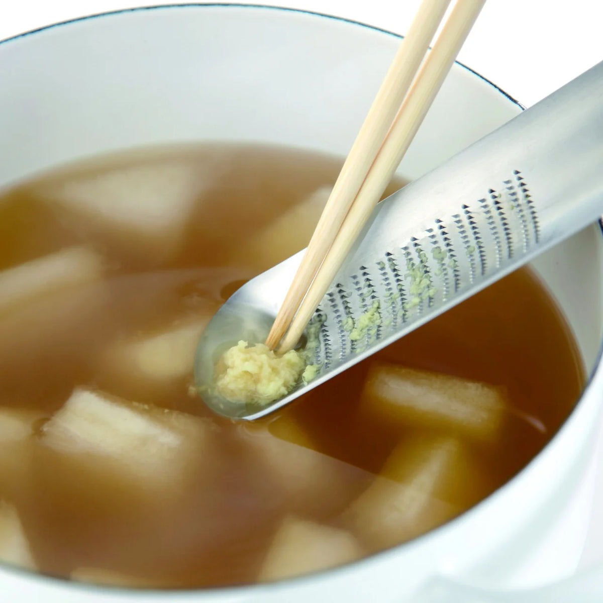 Grating ginger into soup with the Oros grater