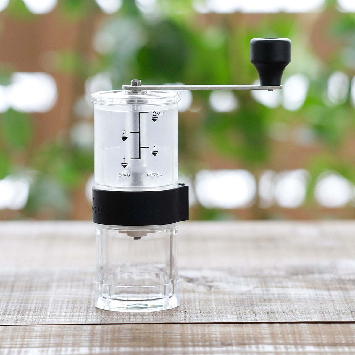Clear manual coffee mill with measuring marks on a wooden table