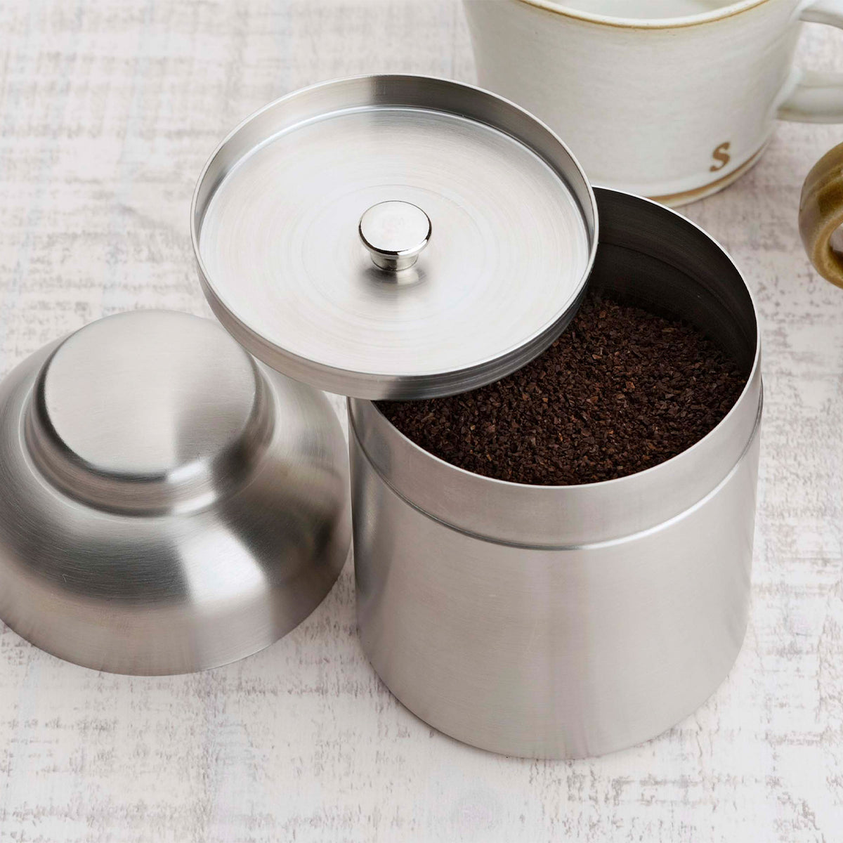 Open canister filled with ground coffee