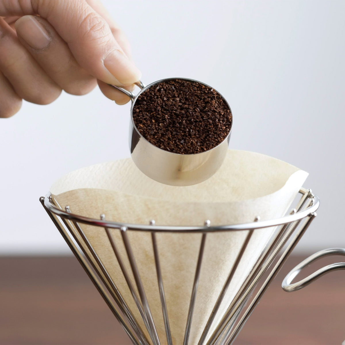 Measuring ground coffee into a wire dripper