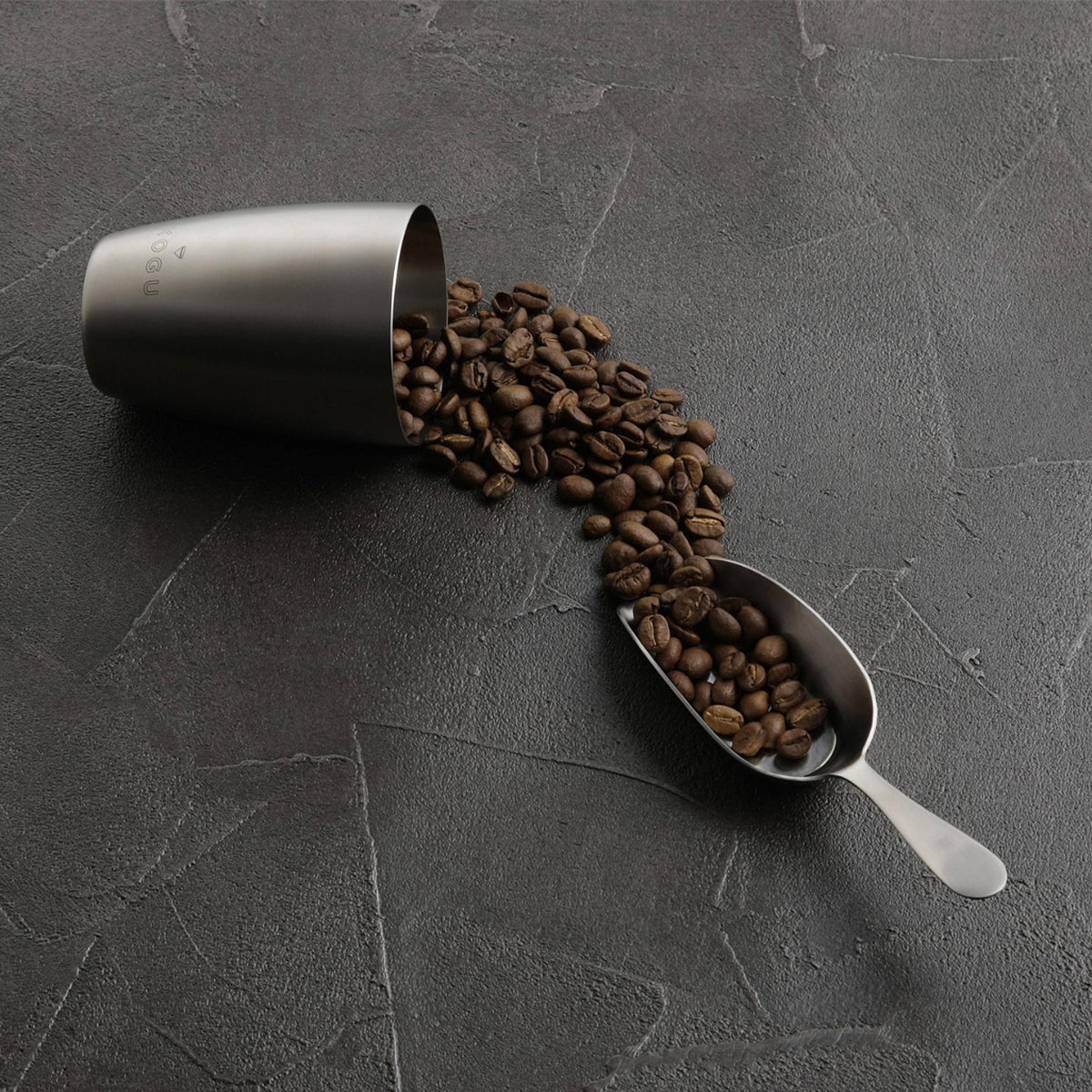 Scoop measure with coffee beans on a dark table