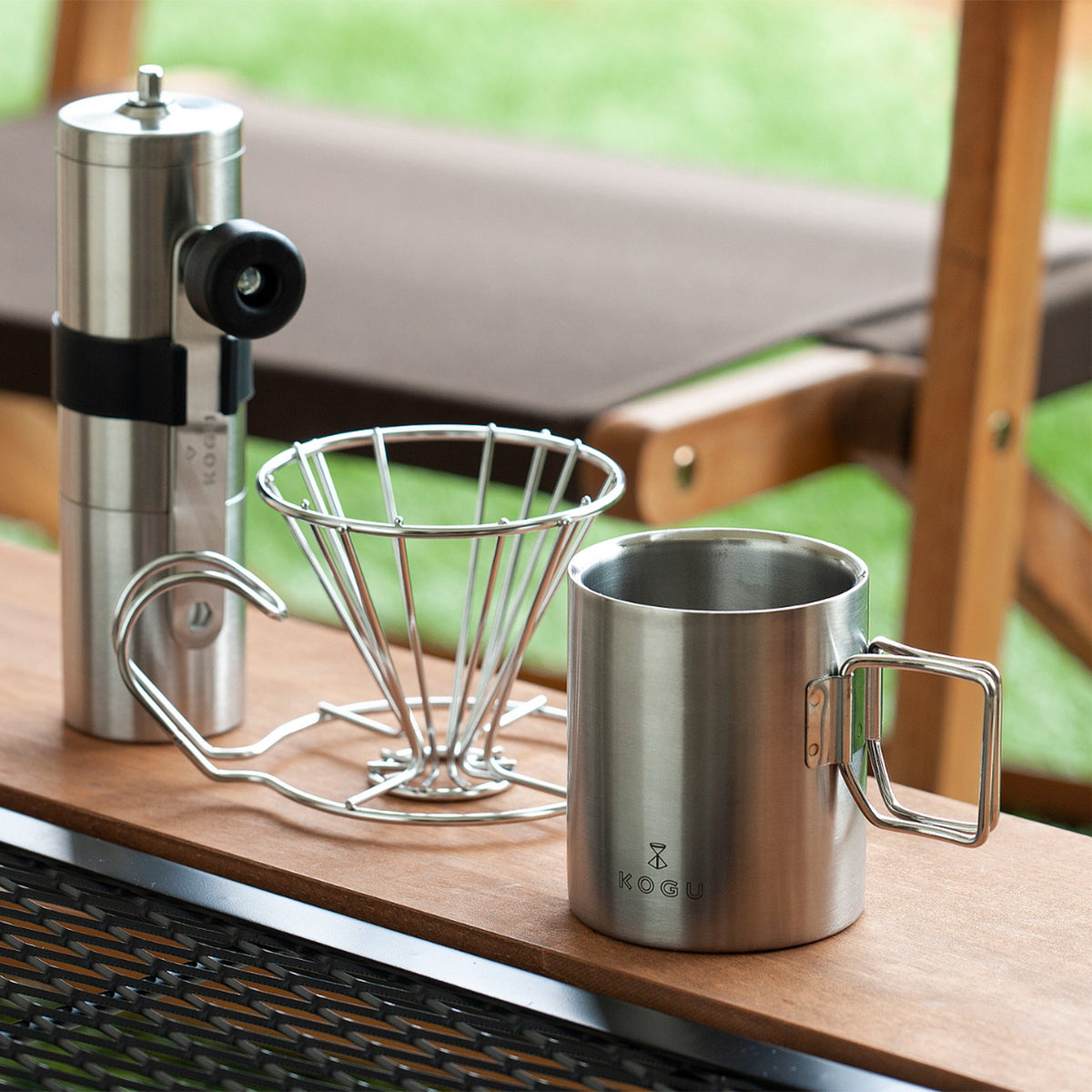 Stainless mug with a coffee mill and dripper stand outdoors