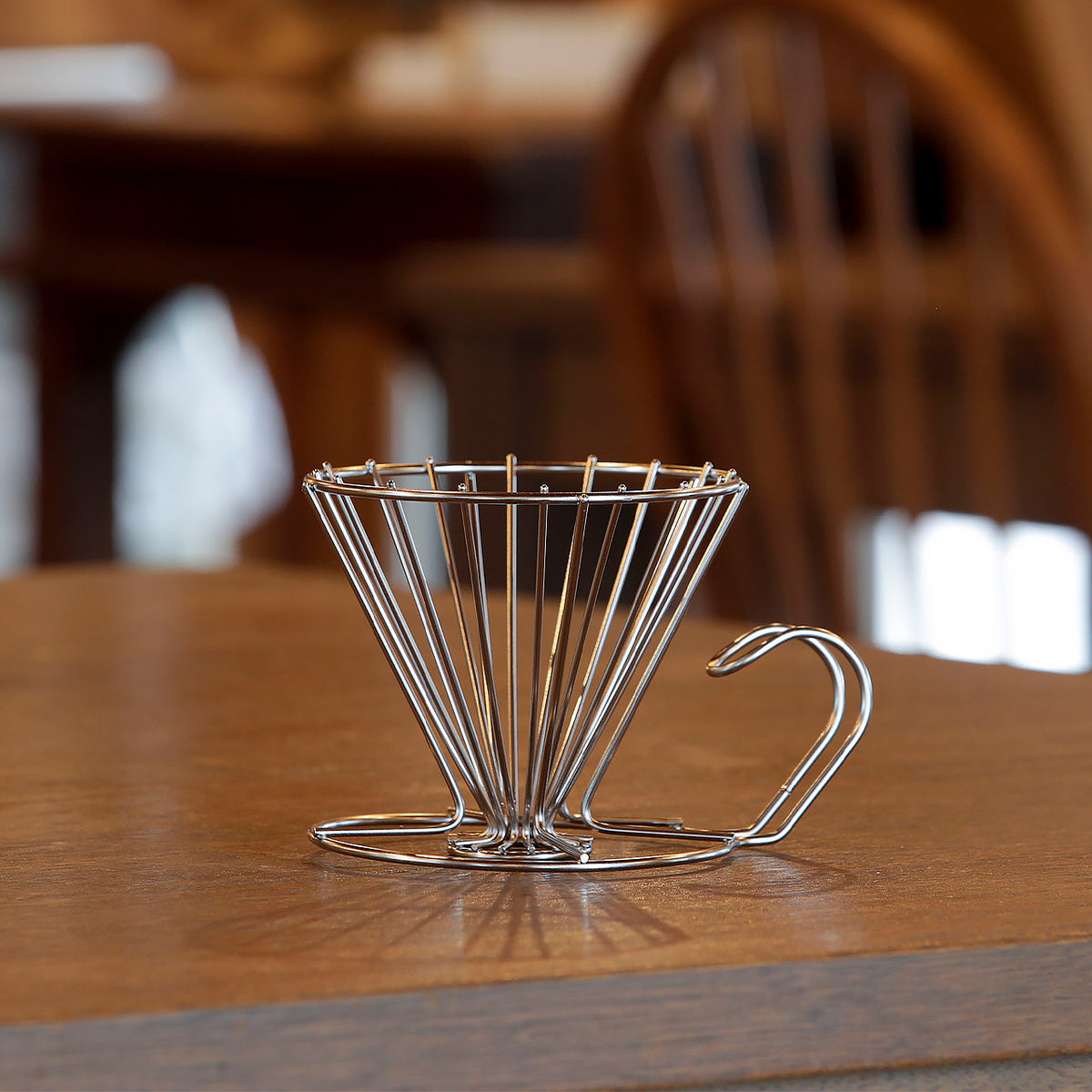Stainless steel wire coffee dripper on a wooden table