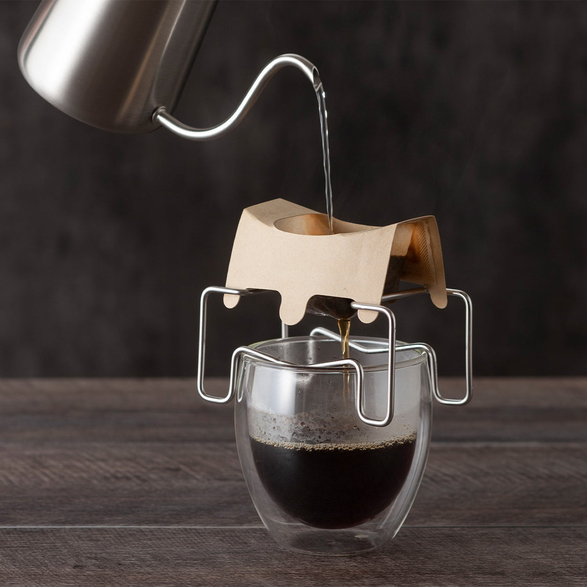 Pouring water into a drip bag on the stand, dark background