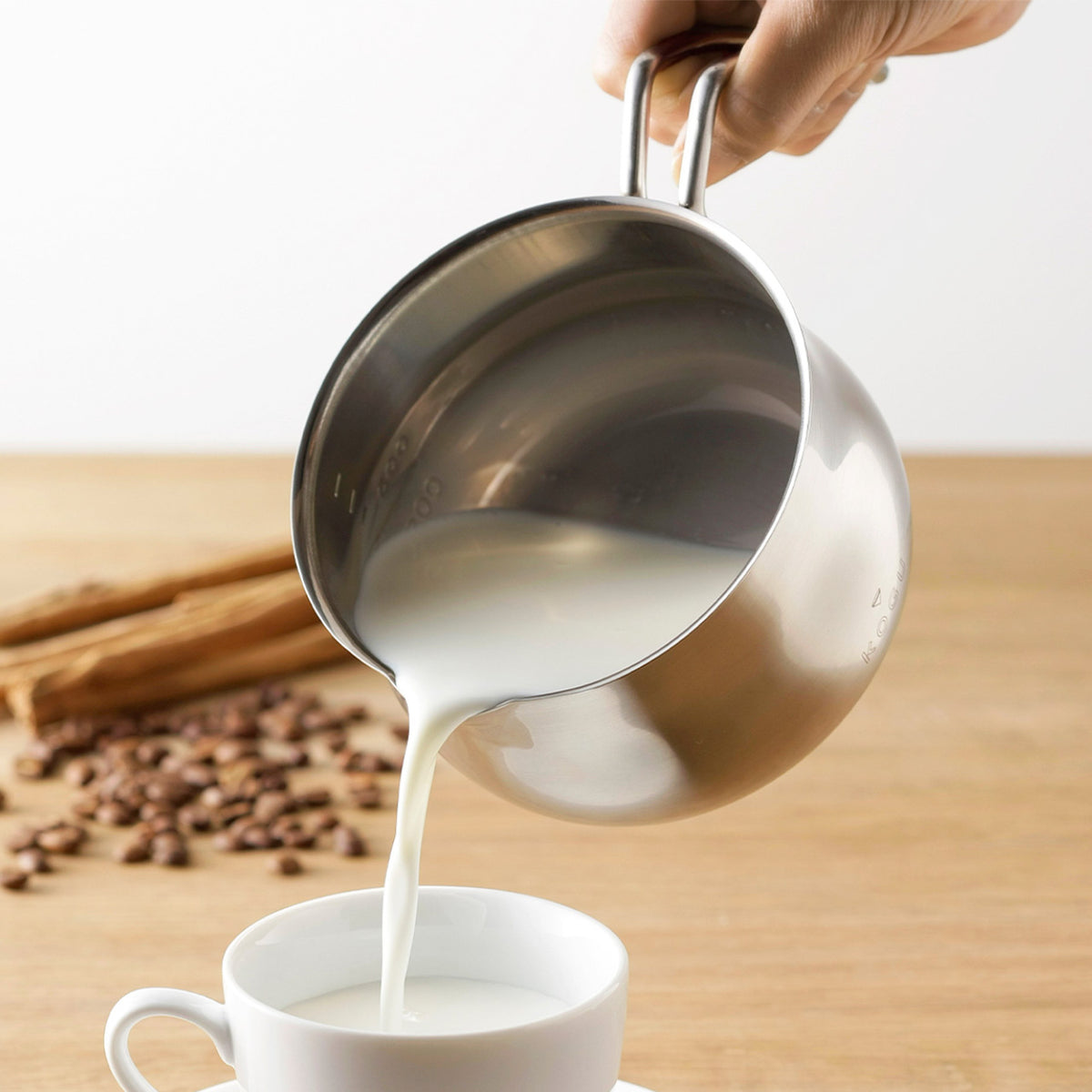 Pouring milk from the wide spout of the milk pan