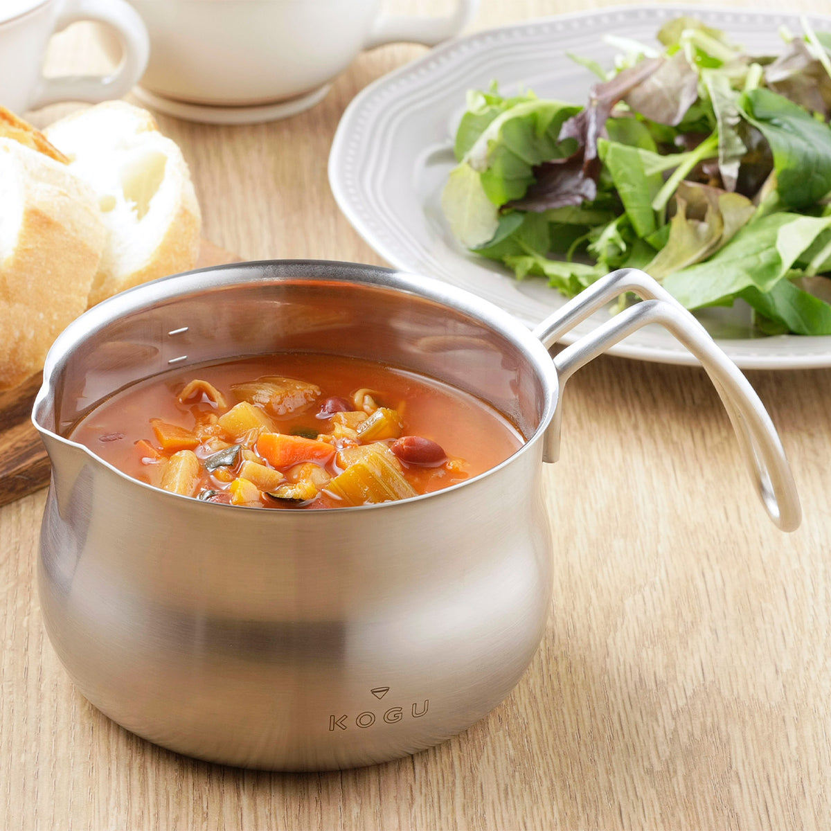 Soup served in the stainless milk pan with salad