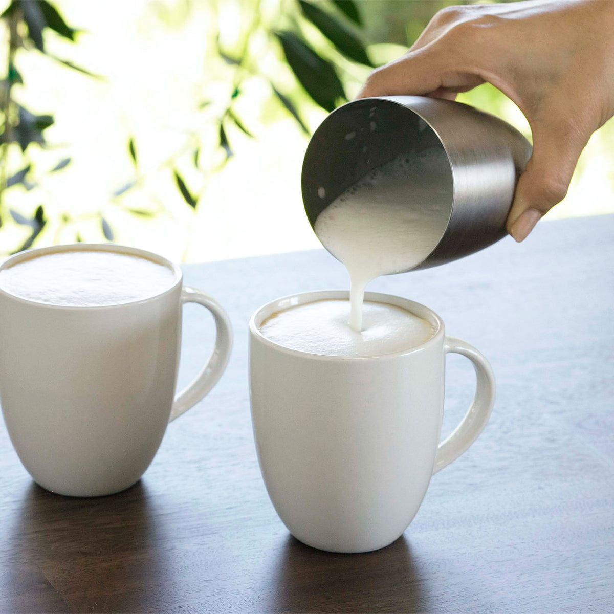 Pouring milk foam into coffee to make lattes