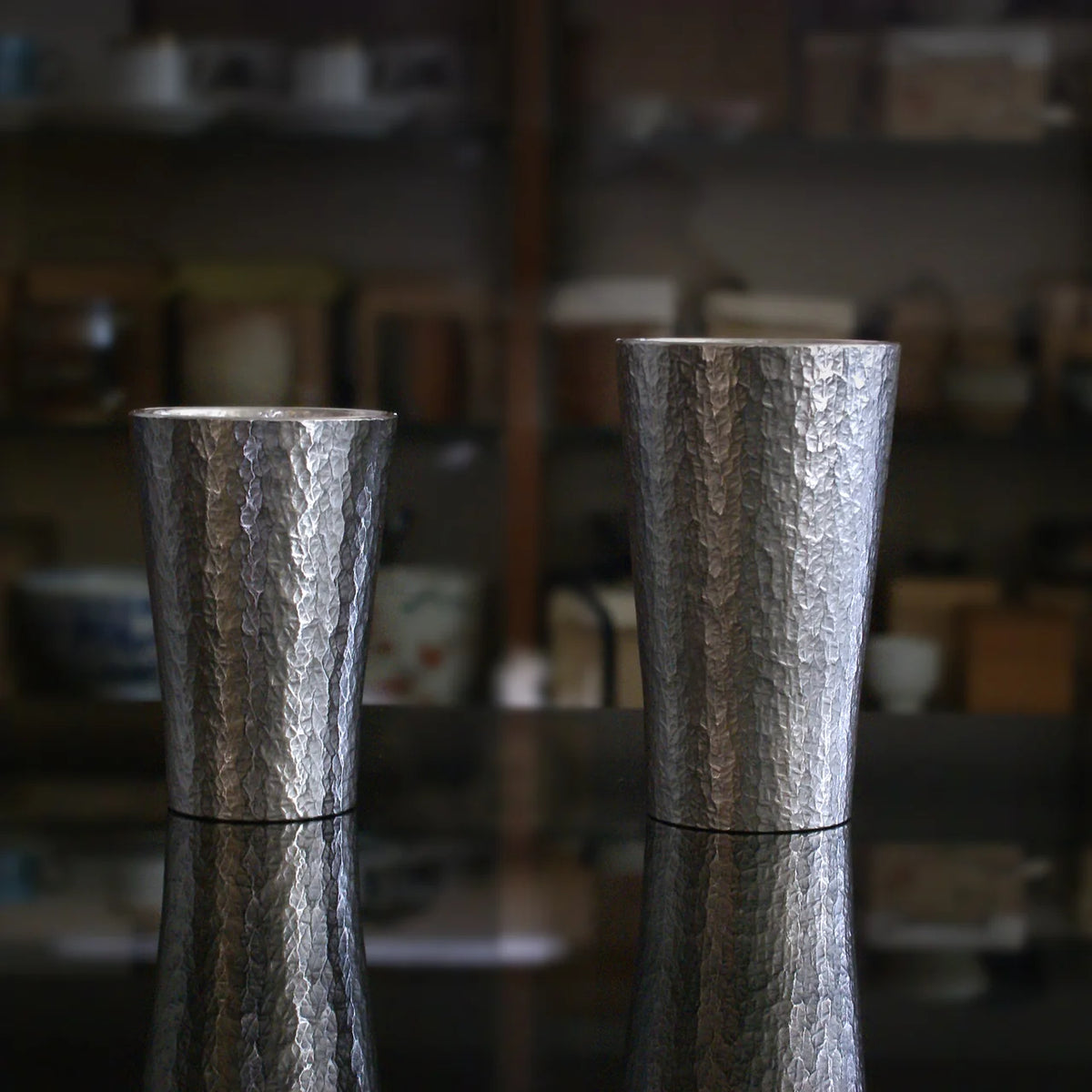 Two Rikka tin tumblers on a dark table
