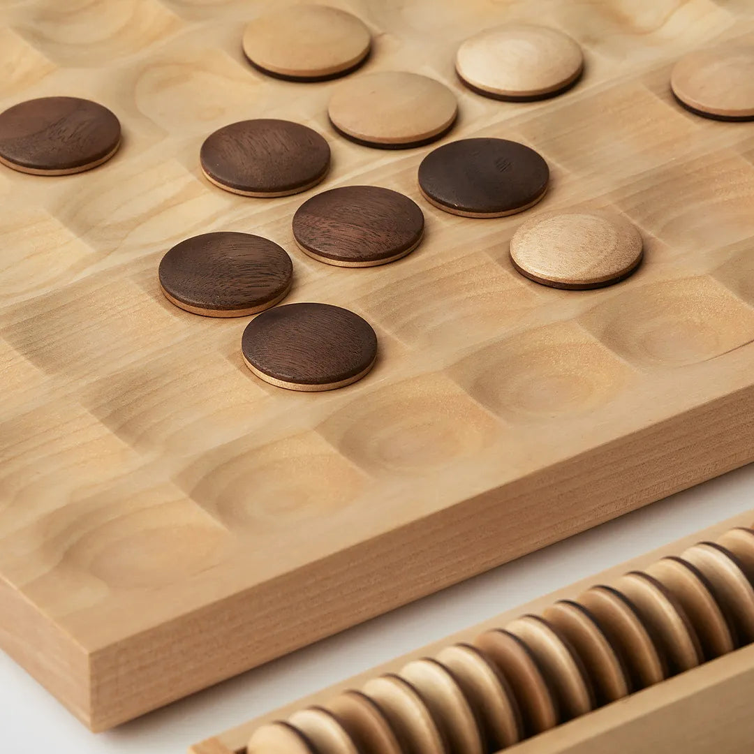 Walnut and birch reversi pieces resting in the round hollows of the board